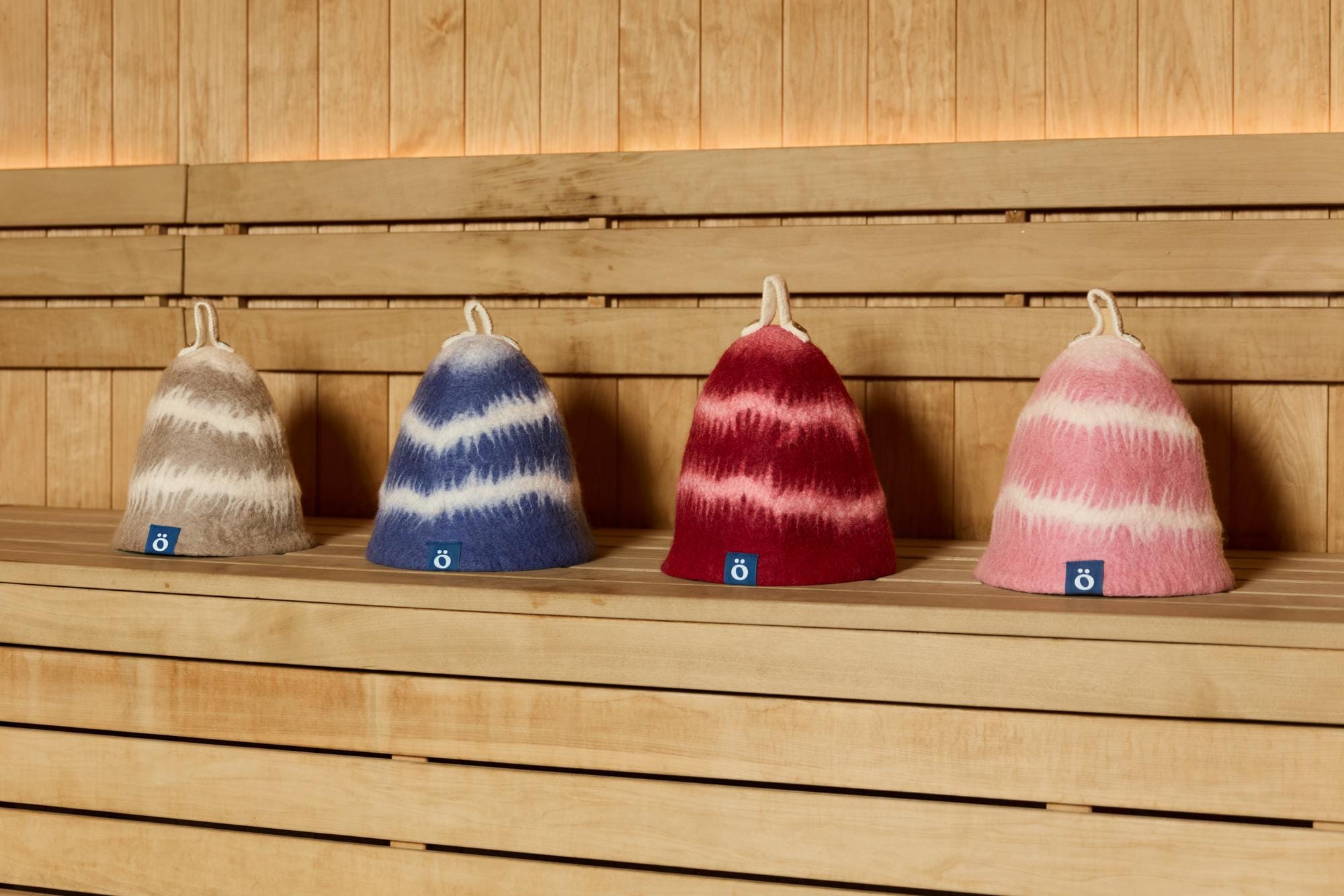 moss, lake, ember and flush hats in a row on a sauna bench